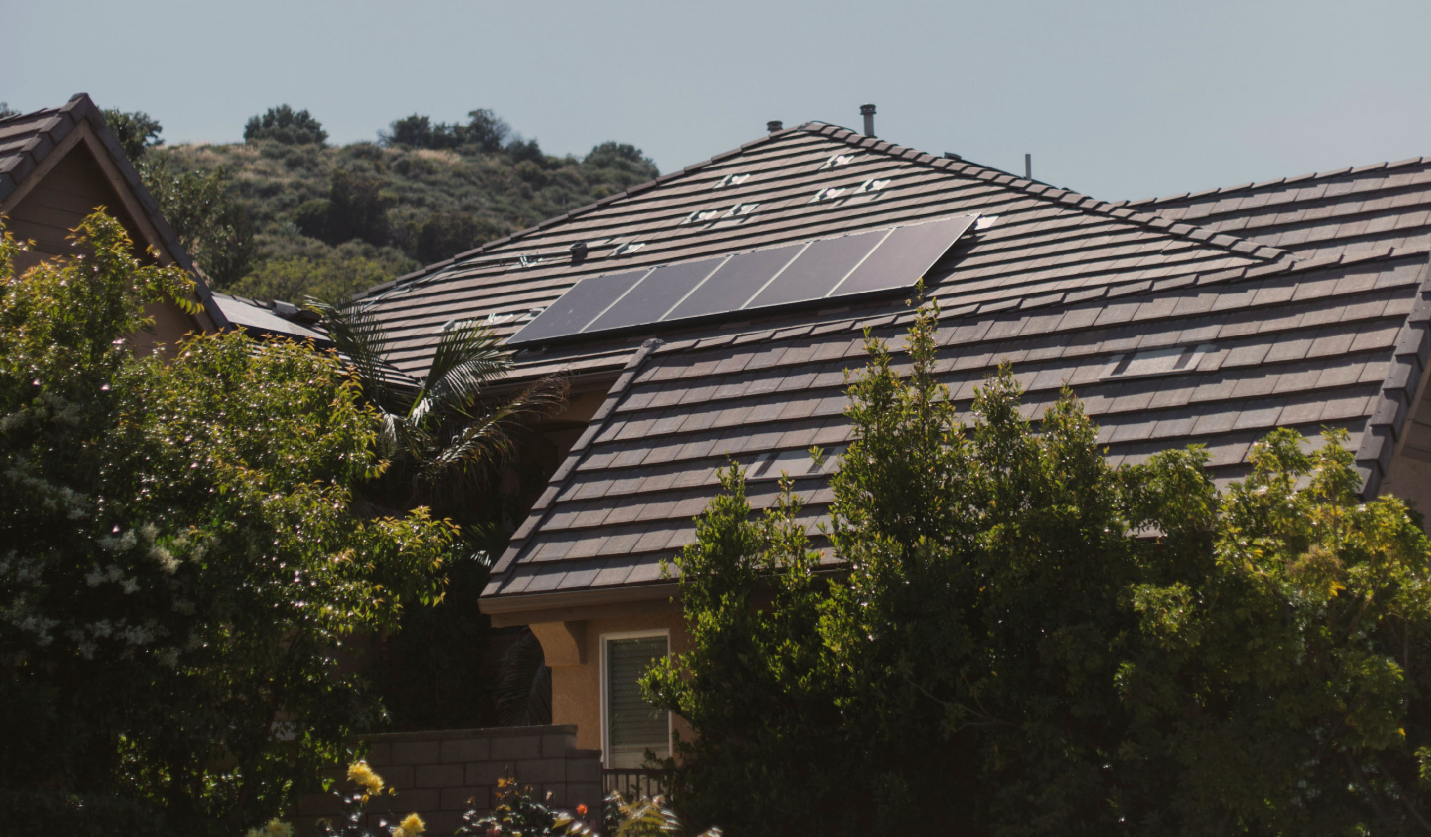 A house with solar panels installed on the roof, surrounded by trees.